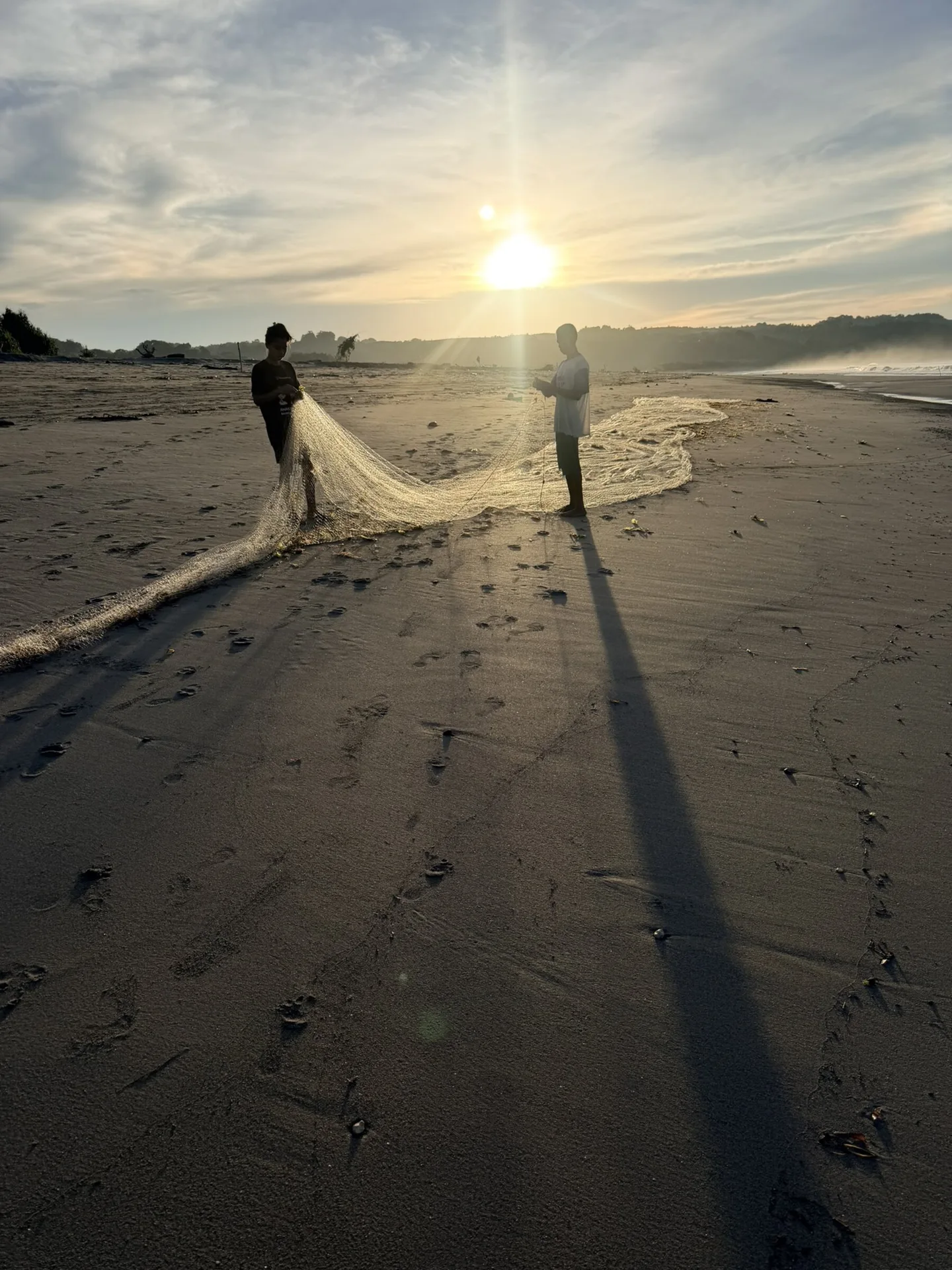 A fisherman casting his net at sunset